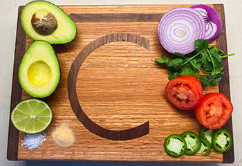 Fresh guacamole ingredients arranged on a Bar C Meat Company cutting board